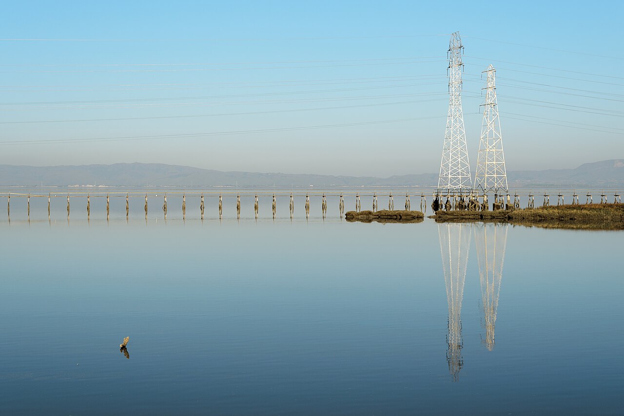 Des pylônes électriques se reflètent dans l’eau à Palo Alto Baylands